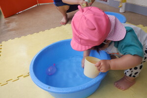 コップやお皿に水を入れてみたり、手でまぜてみたりと水の感触を楽しんでいます