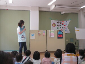 子どもの作品の説明をしている職員と聞いている子どもたちの写真