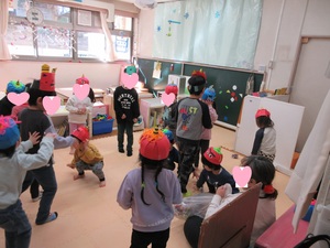 手作りの鬼の帽子をかぶって新聞紙の豆を投げる2歳児