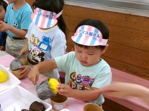 アイスクリーム屋さんになってアイスをカップに入れている写真