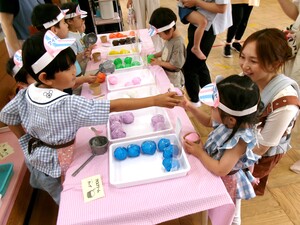 アイスクリーム屋さんになった子どもがアイスクリームを渡している写真