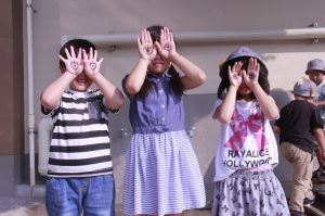 写真：手に目を描いて顔に当てているこどもたち