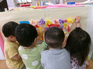 丸めた花紙をこいのぼりに貼る2歳児の子どもたち