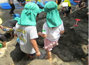 泥の中に足を入れて遊ぶ子どもたち