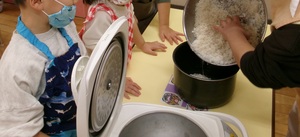 研いだお米を炊飯器のお釜に入れる様子を見る子どもたち