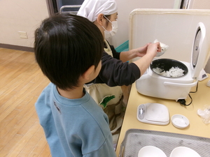 保育室で炊飯して、炊けたごはんをよそってもらう様子