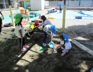 写真：砂場で穴を掘ろうとする4，5歳児の子どもたち