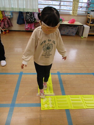 目隠しをしながら手作りの点字ブロックの上を歩いている写真です。