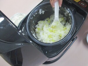 炊飯器に入ったサツマイモごはんをよそっている