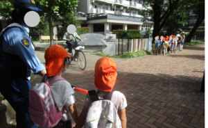 警察官の方とともに通り過ぎる自転車をまつ子どもたち