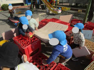 園庭でバスマットを使いお家作りをしています