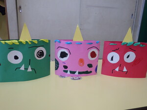 3歳児クラスが作った鬼の写真。画用紙で作った顔にサインペンで顔を描き、リボンを通して髪の毛にしている。頭に被れるようになっている。