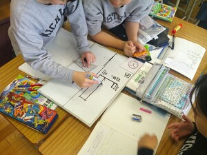 写真：班で相談してミニホワイトボードに図を描く様子