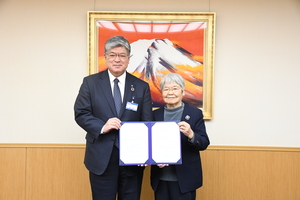 協定書を持つ坂口代表理事（右）と坂本区長（左）